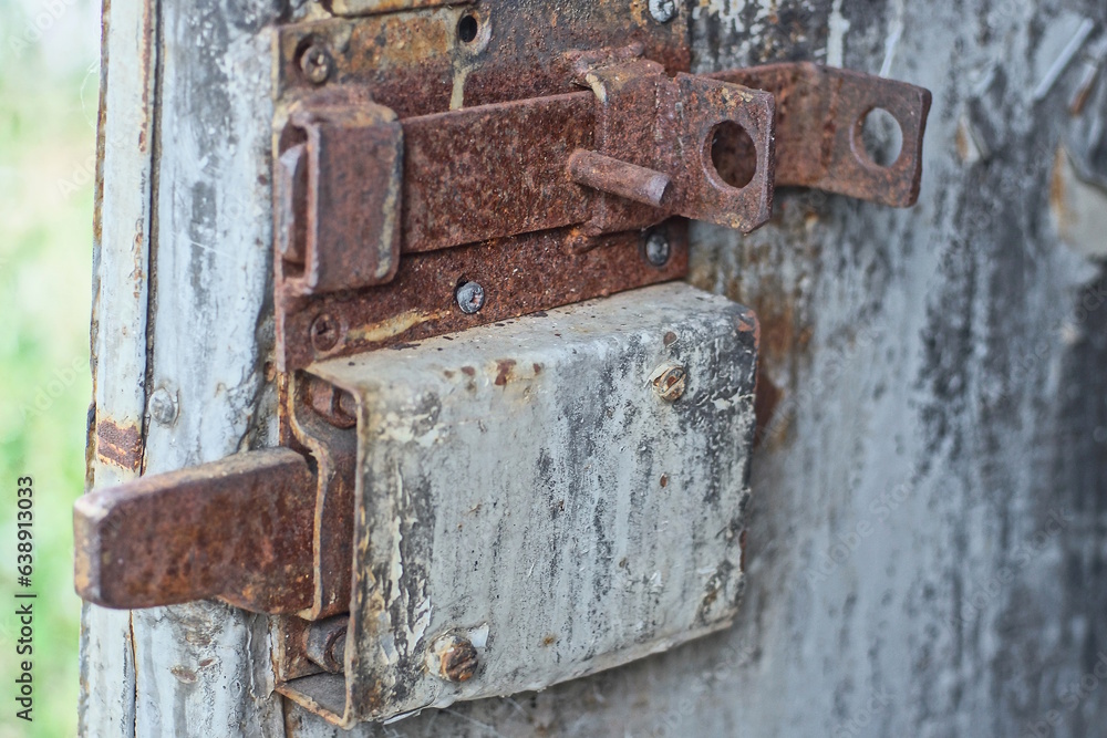 part of an old door with a brown rusty iron latch and a gray overhead metal lock part of an old door with a brown rusty iron latch and a gray overhead metal lock