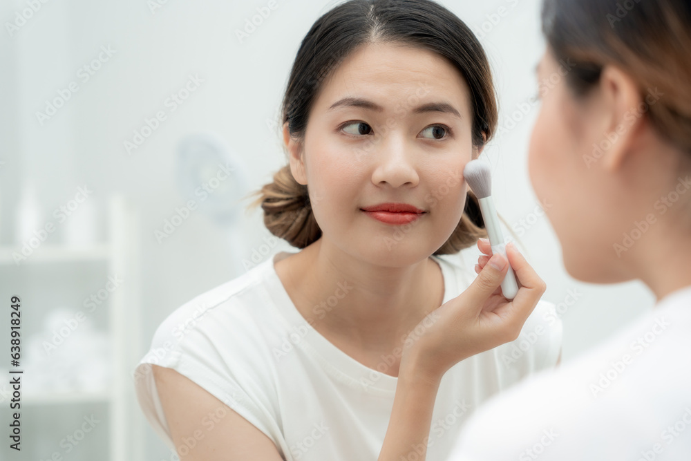 Beautiful Asian woman sit in front of a mirror and smile on makeup. face of a healthy woman applying makeup. Advertisement, lifestyle , cosmetics, makeup accessories, beauty activity, beautician Beautiful Asian woman sit in front of a mirror and smile on makeup. face of a healthy woman applying makeup. Advertisement, lifestyle , cosmetics, makeup accessories, beauty activity, beautician