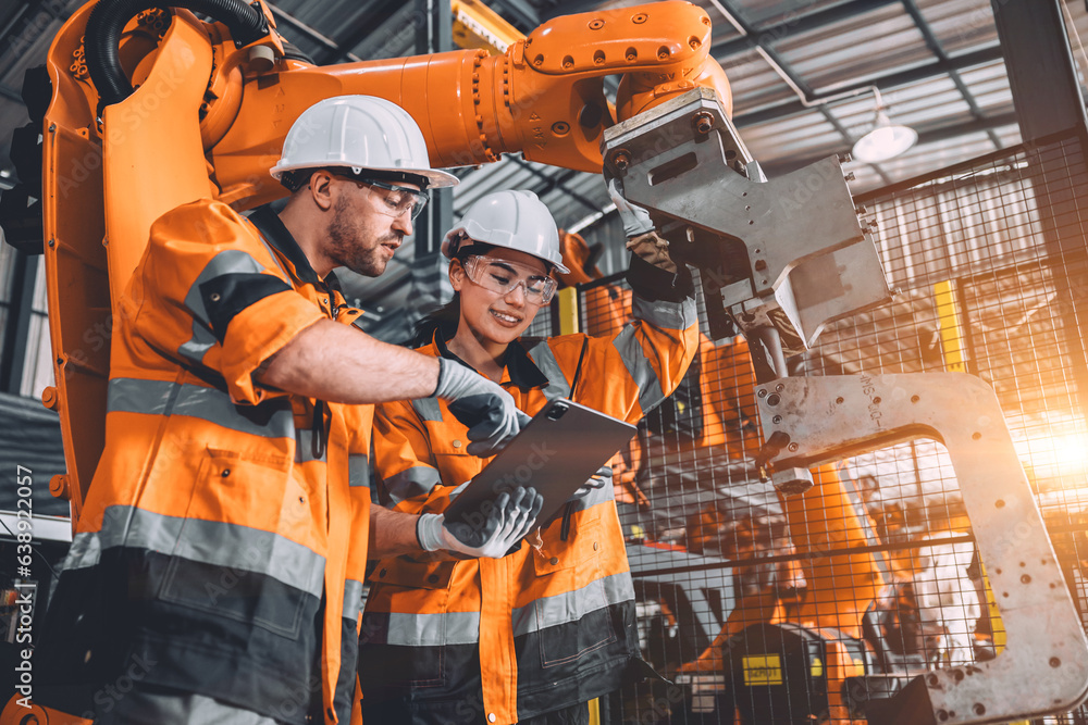 Engineer team service robot welding working in automation factory. People worker in safety suit work robotic arm software programming or replacing part in automated manufacturing industry technology.