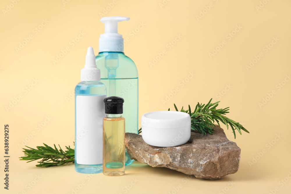Bottles with cosmetic products, stone and rosemary on beige background Bottles with cosmetic products, stone and rosemary on beige background