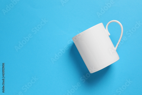 One white ceramic mug on light blue background, top view. Space for text