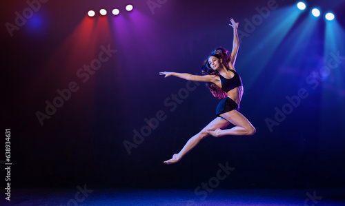 young performer of modern choreography dancing in the spotlights on a black background.