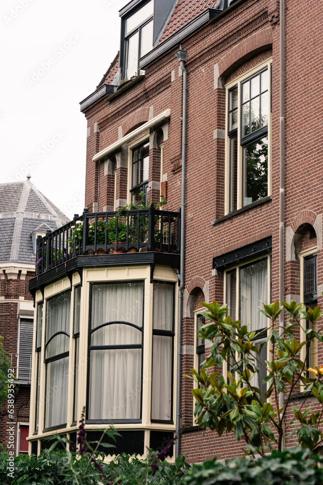 Naklejka premium part of typical red building in Amsterdam, Netherlands, summer, green trees, cloudy