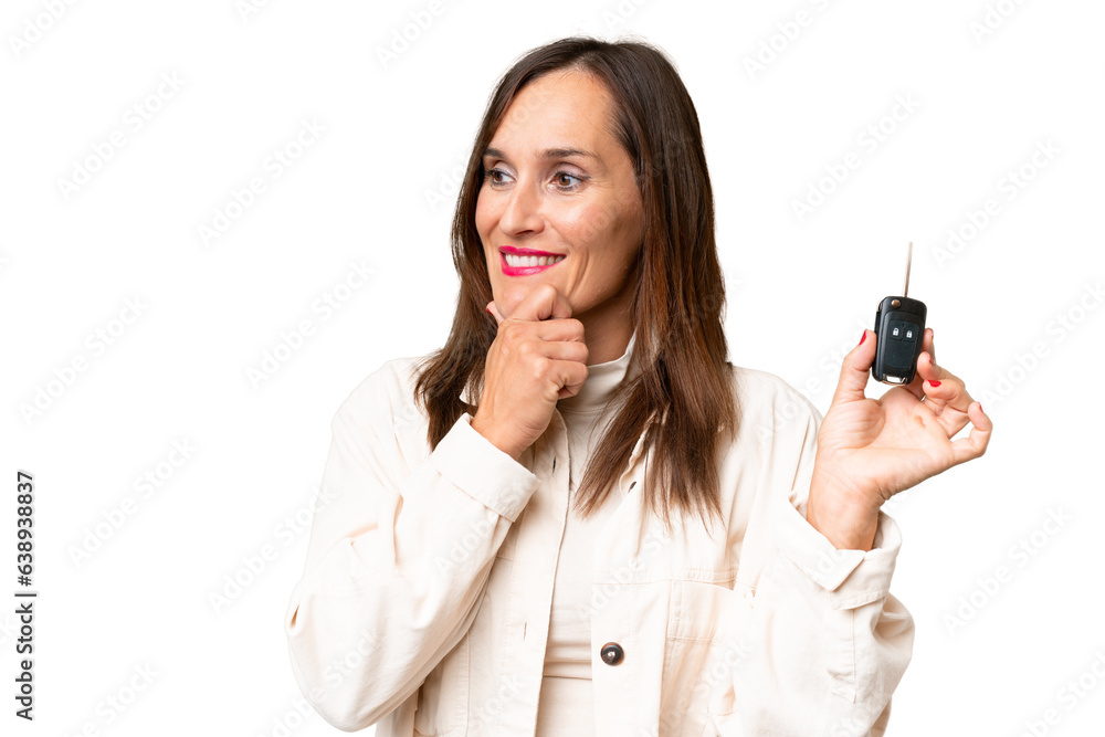 Middle-aged woman holding car keys over isolated background thinking an idea and looking side Middle-aged woman holding car keys over isolated background thinking an idea and looking side