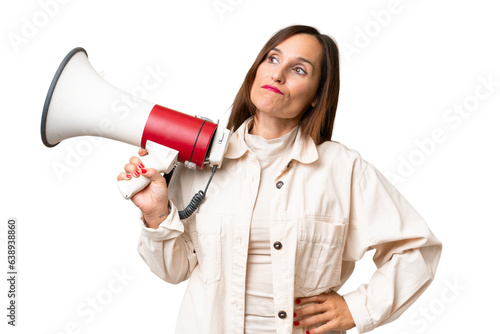 Middle-aged caucasian woman over isolated background holding a megaphone and thinking