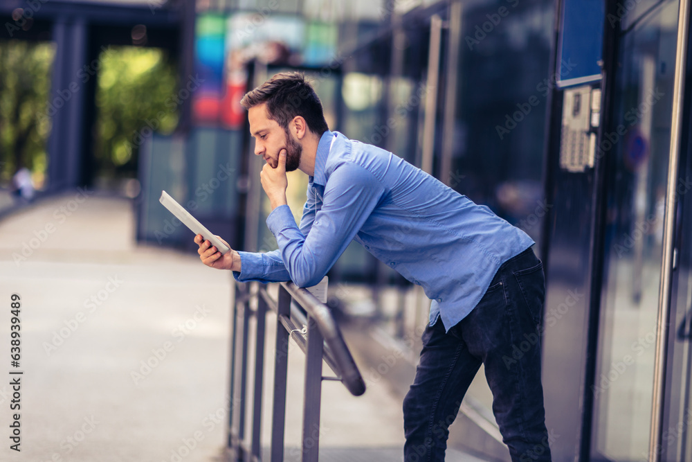 Businessman is outside and he has to work so he is using digital tablet Businessman is outside and he has to work so he is using digital tablet