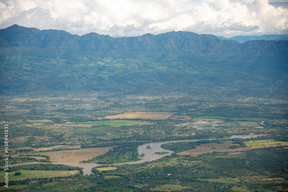 Naklejka premium Aerial view of a river with crop fields around it in a tropical climate in the department of Huila. Colombia.