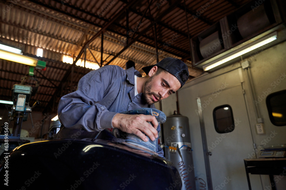 Bearded mechanic repairing motorcycle in garage