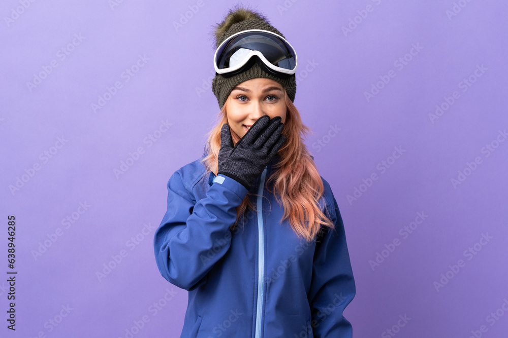 Skier teenager girl with snowboarding glasses over isolated purple background happy and smiling covering mouth with hand Skier teenager girl with snowboarding glasses over isolated purple background happy and smiling covering mouth with hand
