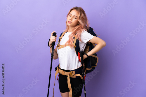 Teenager girl with backpack and trekking poles over isolated purple background suffering from backache for having made an effort