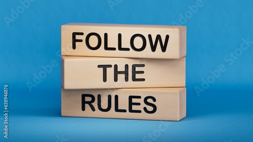 Follow the rules symbol. Concept words Follow the rules on wooden blocks. Business and follow the rules concept. Copy space.3D rendering on blue background.
