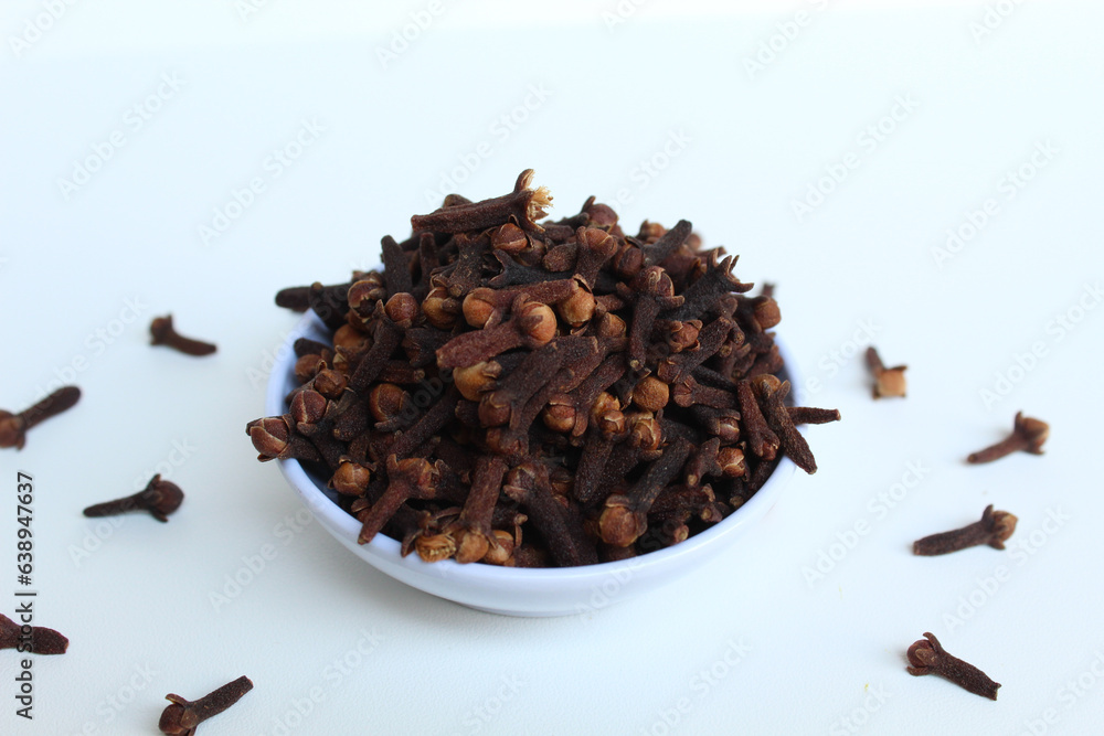 Obraz premium Dried clove or he aromatic flower buds of Syzygium aromaticum, spice from Indonesia. In a small white bowl. Isolated on white background