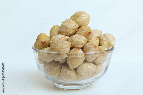 Dried Indonesian Candlenuts, or Kemiri, the seed of Aleurites moluccanus inside a transparant bowl, isolated in white background