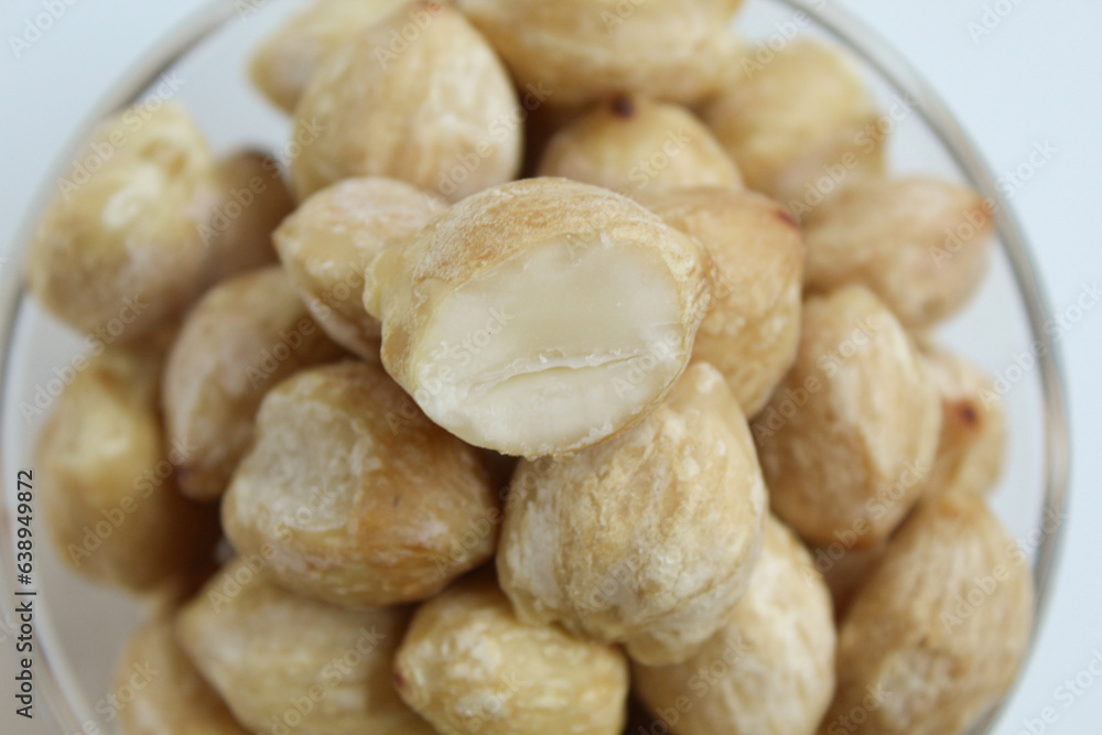 Dried Indonesian Candlenuts, or Kemiri, the seed of Aleurites moluccanus inside a transparant bowl, isolated in white background. Flat lay or top view Dried Indonesian Candlenuts, or Kemiri, the seed of Aleurites moluccanus inside a transparant bowl, isolated in white background. Flat lay or top view