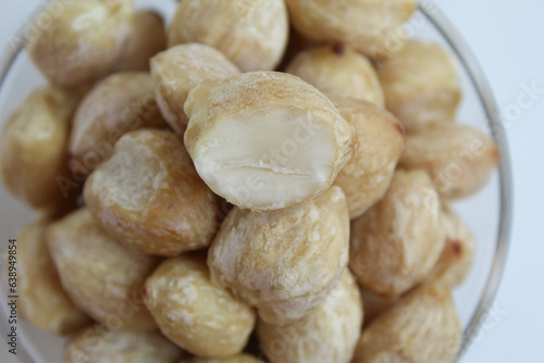 Dried Indonesian Candlenuts, or Kemiri, the seed of Aleurites moluccanus inside a transparant bowl, isolated in white background. Flat lay or top view