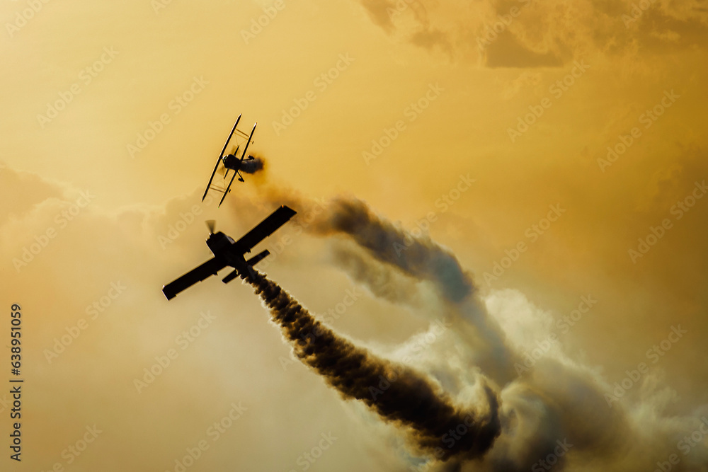 Aviones compitiendo , en una serie dorada , un atardecer a contra luz , mostrando estelas de humo de sus motores , carrera en cielos Mendocinos Arg. - obrazy, fototapety, plakaty 