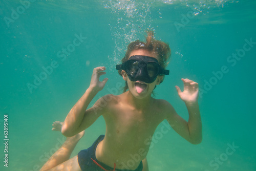 Boy having fun and showing tongue underwater