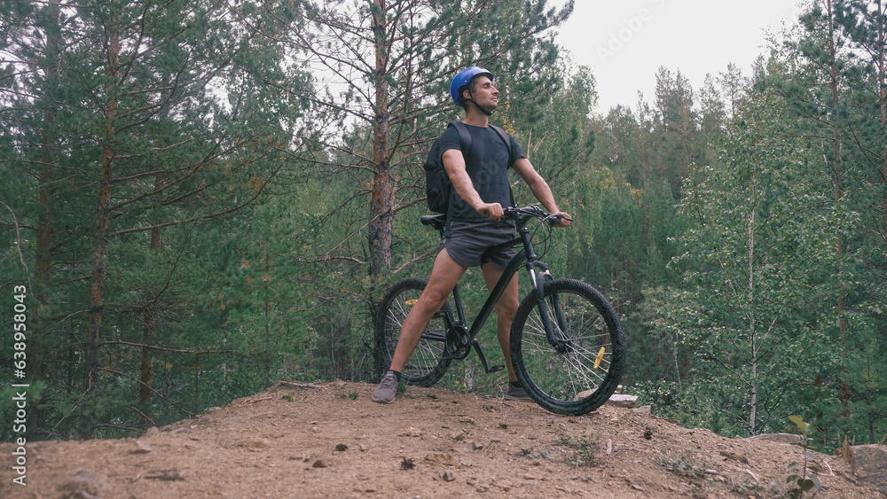 mountain bike.A man in a protective helmet and sports equipment stopped on rough terrain and looks away.Active lifestyle
