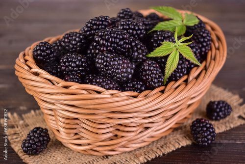 Fresh blackberries in a basket on a dark wooden background.
