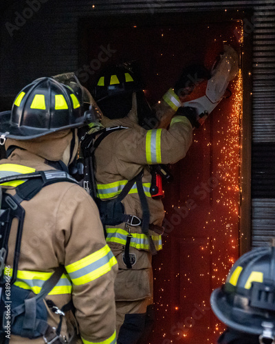 Canvas Print firefights use an electric saw to cut through the door of a building during a training exercise