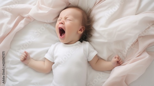 Cute baby sleeping and yawning on white sheets, with copy space.