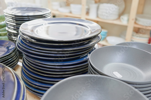 Stacked dishes in a pottery store. Shopping handcrafted ceramic tableware and utensils in a craft shop. 