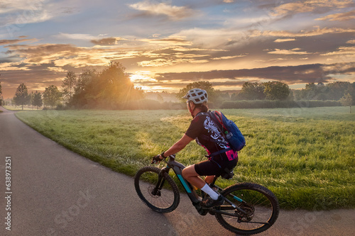 Fototapeta Naklejka Na Ścianę i Meble -  nice woman with electric mountain bike, cycling in moody morning light on the Neckar valley bicycle path near Ludwigsburg, Baden Württemberg, Germany