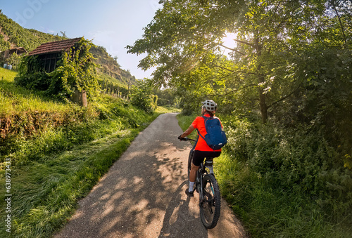 nice woman with electric mountain bike, cycling in moody morning light on the Neckar valley bicycle path near Ludwigsburg, Baden Württemberg, Germany photo