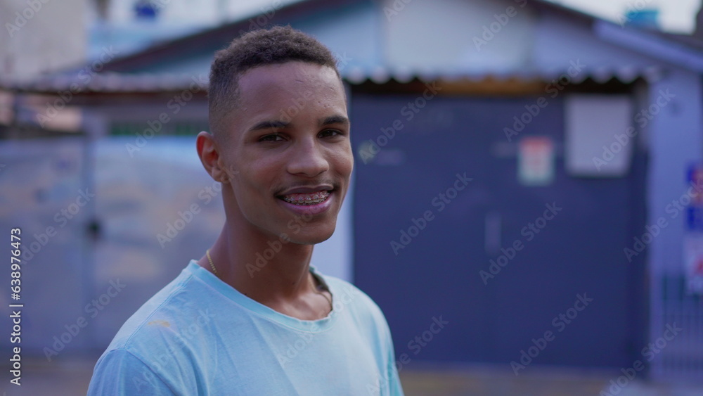 Fototapeta premium Portrait of a young black South American man smiling at camera, close-up face of a cheerful happy Brazilian individual with braces