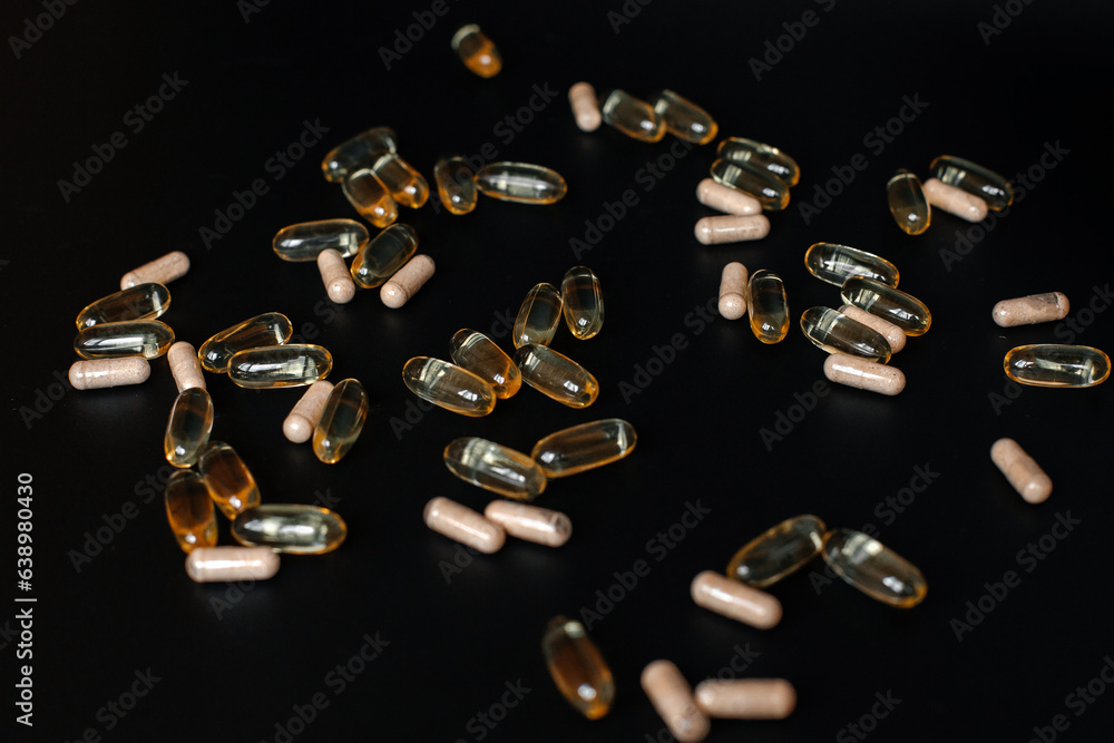 Fish oil capsules and probiotics on a black background