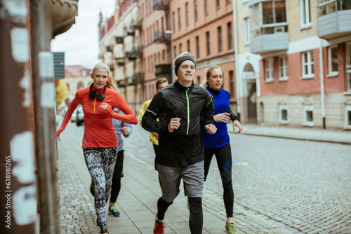 Young group of friends running and jogging together in the city during winter or autumn
