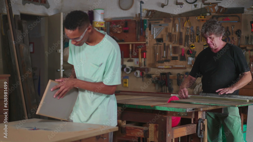 Carpentry scene of apprentice and master carpenters working at wood craftsmanship workshop. Candid workers engaged with job occupation
