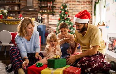 Young caucasian family opening presents during christmas and the new year holidays in the living room in the morning