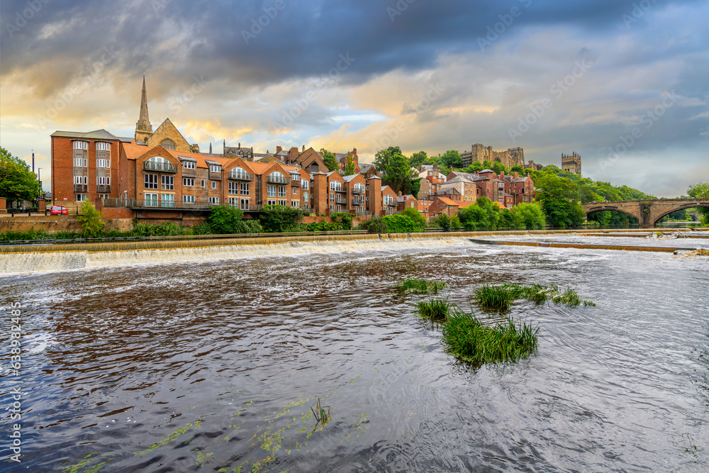 Fototapeta premium The skyline of the city of Durham including the Romanesque Durham Cathedral and Durham Castlen, now a university, is seen behind the River Wear under a dramatic sky in Durham, England UK.