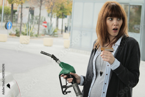 Fotografie A woman at the petrol station looks terrified and dismayed at the soaring prices in disbelief at a petrol station, her face impression of shock as she gazes at the high fuel cost