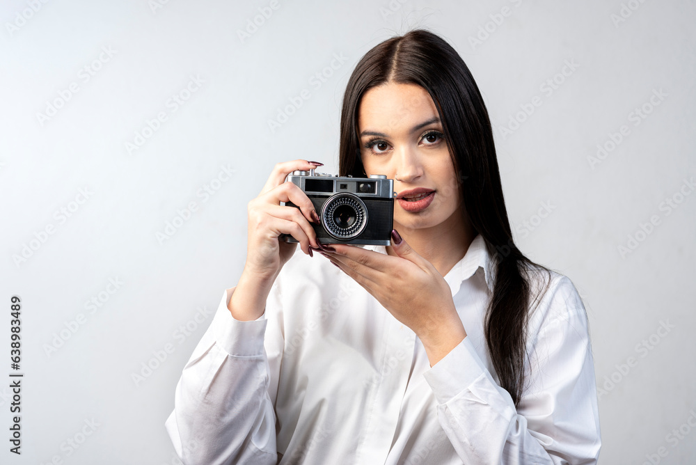 young latin woman holding an old photo camera dressed in white shirt and white background young latin woman holding an old photo camera dressed in white shirt and white background