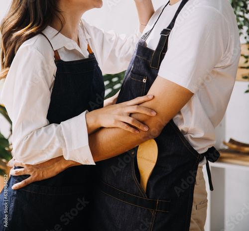 Happy young adult couple making breakfast and drinking coffee together in cozy home kitchen in morning at home. Preparing meal and smiling. Lifestyle, leisure and Love concept. © ARMMY PICCA