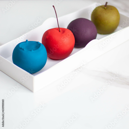 Modern realistic fruit pastries made of chocolate and mousse. Red apple, green apple, blueberry and passion fruit for cafe or restaurant photo