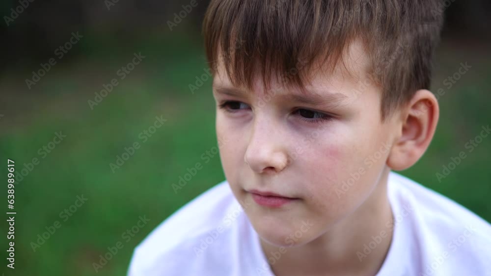 A nine-year-old boy sits quietly on the street. close-up portrait. A nine-year-old boy sits quietly on the street. close-up portrait.