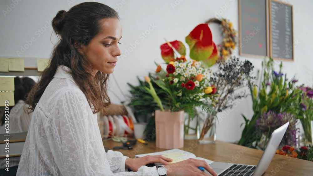 Serious florist work laptop digital device in flowers store. Focused woman work. Serious florist work laptop digital device in flowers store. Focused woman work.