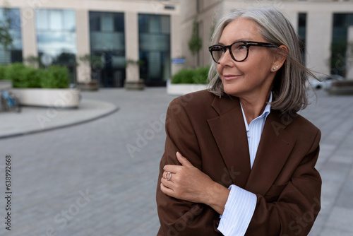 portrait of a successful well-groomed pretty gray-haired woman pensioner dressed in an elegant suit on the street