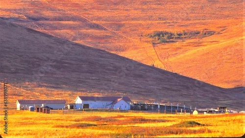 National Bison Range Montana - Out buildings at the base of a vast,  grassy hillside turned a golden brown.