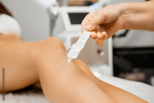 Close up laser epilation gel on the spatula on the background of woman legs before the laser epilation procedure. 