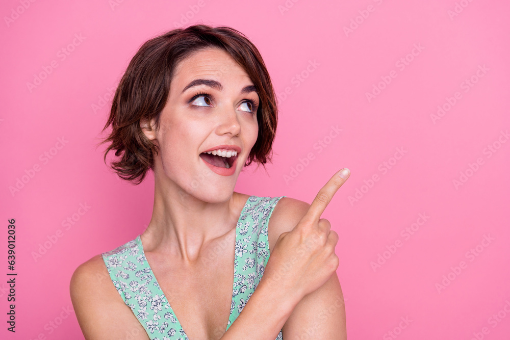 Photo of attractive young girl brown hair wear green top indicating finger mockup wow crazy ad news isolated on pink color background Photo of attractive young girl brown hair wear green top indicating finger mockup wow crazy ad news isolated on pink color background
