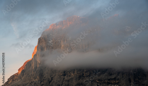 Foggy rocky mountain landscape at sunrise with blue sky.