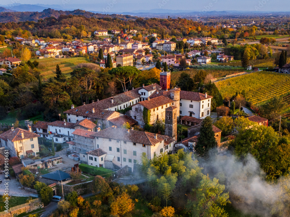 Autumnal magic and emotions on the ancient village. Between vineyards and colorful woods. Friuli. Top view