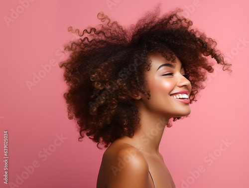 beautiful woman portrait with afro hair in profile smiling on pink background