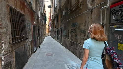 Genoa, Liguria, Italy. June 3, 2023. Engaging pov footage walking through the alleys of the historic center, a middle-aged woman precedes us. She explores and discovers Genoa. photo