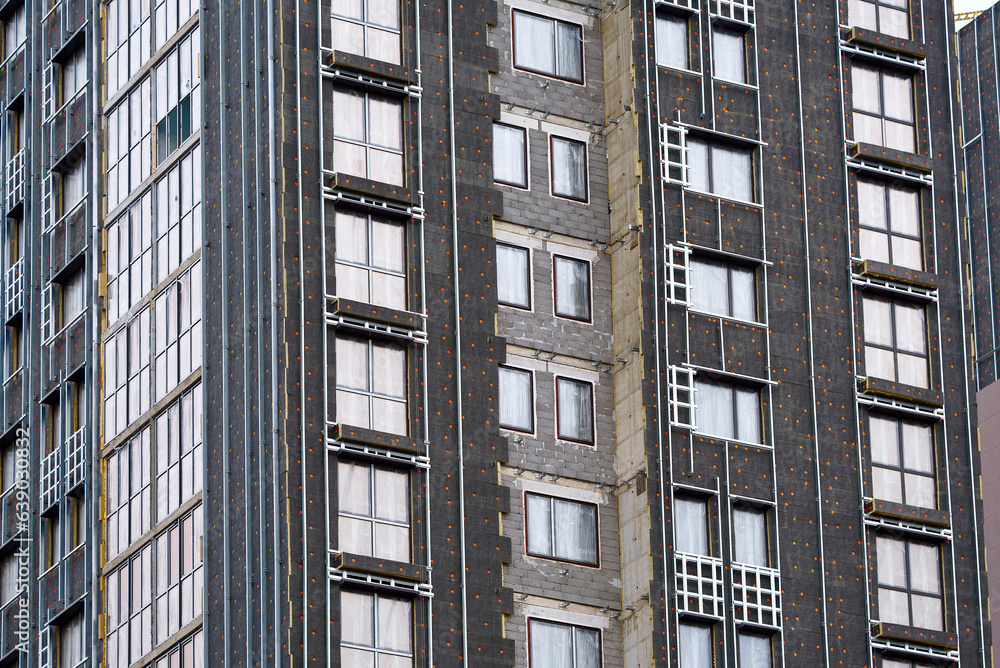 Thermal insulation of building wall, decorative exterior cladding. Insulate building with rock wool, installing ventilated facade. Insulation of external wall of high-rise residential building. Thermal insulation of building wall, decorative exterior cladding. Insulate building with rock wool, installing ventilated facade. Insulation of external wall of high-rise residential building.