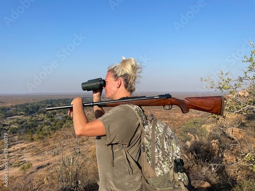 Woman Holding Gun with Backpack Overlooking Mountain with Binoculars in South Africa